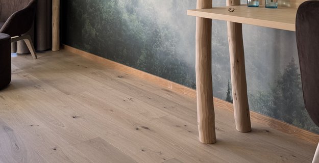 Natural hotel room with oak parquet flooring, soft green forest wallpaper, and natural interior.