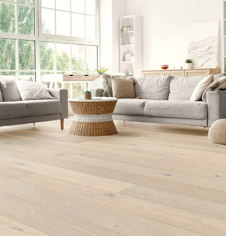 Parkett Landhausdiele Eiche Sylt Helles Wohnzimmer mit grauer Sitzlandschaft und weiß geöltem Eichenparkett