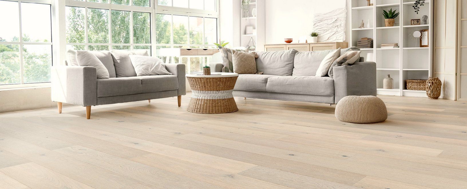 Parkett Landhausdiele Eiche Sylt Helles Wohnzimmer mit grauer Sitzlandschaft und weiß geöltem Eichenparkett